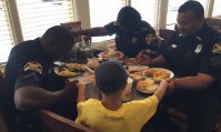 Foto de momento de oração de menino por policiais em restaurante emociona nas redes sociais